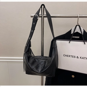 Detail of black leather hobo bag featuring diagonal stitching and adjustable eyelet strap