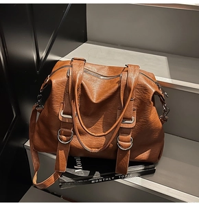 Detail of caramel brown tote bag featuring pleated texture and silver ring hardware
