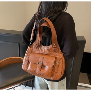 Detail of tan brown leather tote bag with vintage metal buckle and large front flap pocket