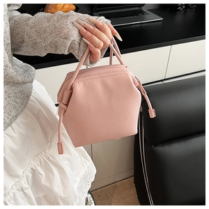 Close-up of pink shell handbag with litchi texture leather and tassel charm detail