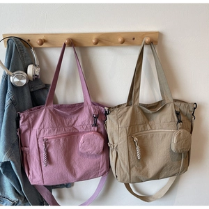 Detail view of large nylon tote bags in pink and khaki featuring round coin purses