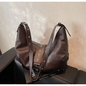 Detail of vintage brown leather tote featuring star rivets and metal eyelet strap