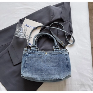 Dettaglio della borsa in denim blu lavato con chiusura metallica e tracolla regolabile