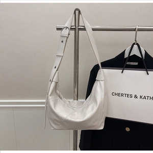 Detail of off-white hobo bag with adjustable silver buckle strap and stitched paneling