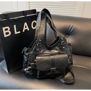 Macro detail of black vintage wrinkled leather tote with multiple pockets and bronze hardware