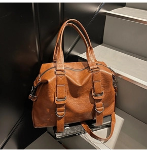 Close-up of caramel brown pebble leather texture and metal buckle on the large tote bag