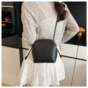 Detail of black lychee grain leather shell bag with side drawstrings and sleek strap