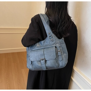 Detail of blue pebbled leather tote bag with functional front flap pocket and metal buckle