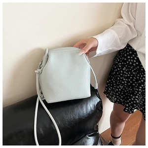 Close-up of light green crossbody bucket bag with textured lychee grain leather detail