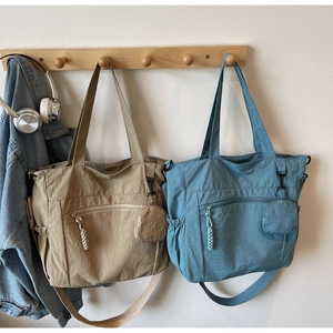 Detail of khaki and blue nylon tote bags with adjustable straps and mini round pouches