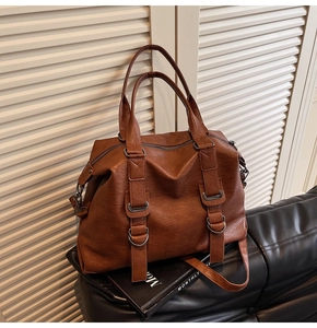 Detail of caramel vintage leather tote bag with metallic buckles and adjustable strap