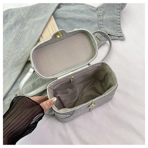 Detailed interior of grey quilted square bag showing zip pocket and gold magnetic closure