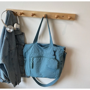Detailed shot of a Morandi blue nylon tote bag with small round pouch on a wooden hook