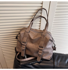 Close-up of brown PU leather tote bag featuring decorative straps and metal buckles