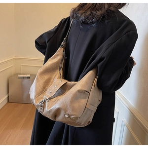 Close-up of beige PU leather hobo bag with star studs and stylish metal hook closure