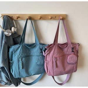Nylon tote bags in blue and pink with matching mini pouches on wooden hooks