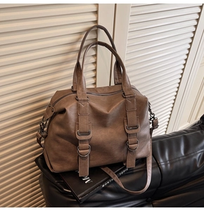 Detailed view of the dark coffee tote bag texture and gunmetal buckle on the leather sofa