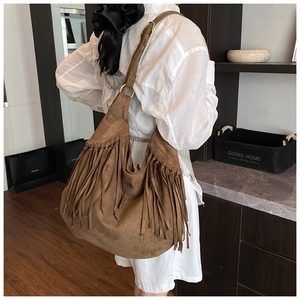 Detail view of brown faux suede tassel tote bag with adjustable shoulder strap and ring