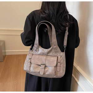 Detail view of taupe faux leather tote bag with buckle accents and adjustable shoulder strap