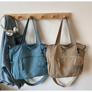 Detail view of nylon tote bags in blue and khaki with mini pouch and shoulder straps