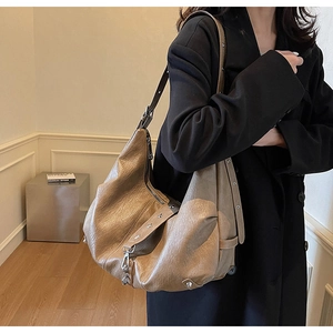 Detail of star-shaped rivets and metallic zipper on a soft brown faux leather hobo bag