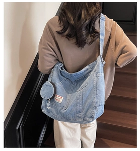 Detail of vintage blue denim crossbody bag with matching round coin purse on wood stairs