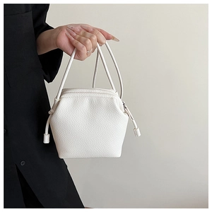 Close-up of minimalist white leather shell bag with textured finish and knotted handle detail