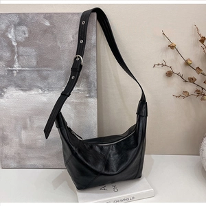 Detail view of black leather hobo bag showing geometric stitching and silver buckles