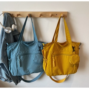 Detail of nylon tote bags in blue and yellow showing detachable strap and round coin purse