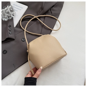 Detail shot of the beige litchi grain texture on this minimal shell crossbody bag