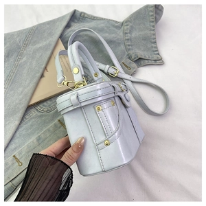 Close-up of light blue denim-style bucket bag with gold rivets and leather belt detail