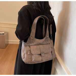 Lifestyle shot of a taupe faux leather tote bag with flap pockets and double straps