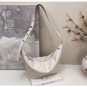 Detail of cream leather crescent bag featuring diagonal stitching and adjustable strap