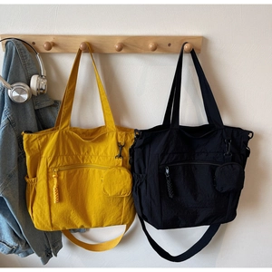 Detail of nylon tote bag with front zipper pocket and round coin purse attachment