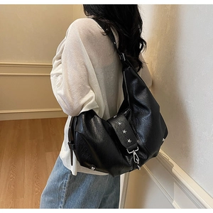 Detail view of large black leather hobo bag with silver star rivets on female model