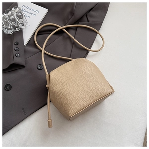 Detail of beige litchi grain leather shell bag with elegant knotted shoulder strap design