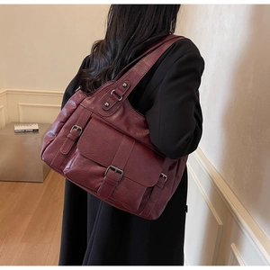 Detail of burgundy tote bag with front buckle pockets and soft textured faux leather finish