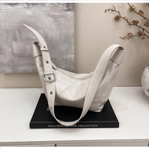 Detail of a large cream hobo bag with wide strap and metallic eyelets on a display