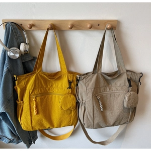 Detail of yellow and khaki nylon tote bags with zip pockets and mini pouch accessories