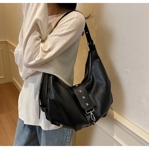 Detail of black leather hobo bag with silver star rivets and soft matte pebble texture