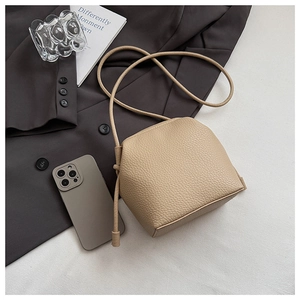 Close-up of beige lychee grain leather mini crossbody bag with knot detail and slim strap