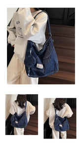 Detail view of large dark blue denim messenger bag with detachable round coin purse charm