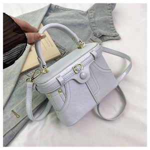 Detail showing the light purple leather box bag with golden hardware and buckle strap