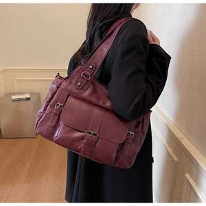 Deep red tote bag made of soft textured leather with elegant buckle detail and pockets