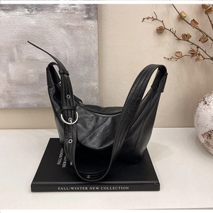 Minimalist black crescent shoulder bag with silver hardware on a stylized display