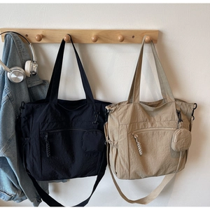 Nylon tote bag detail showing black and khaki options with multi-pocket design on hangers