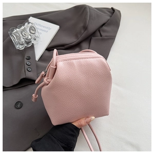 Detail of pink lychee textured leather bag with thin shoulder strap and zipper closure