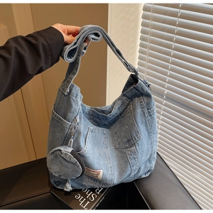 Detail view of washed denim crossbody bag with functional pockets and mini coin purse charm