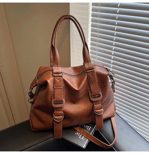 Detail of caramel tote bag showing textured faux leather and metal ring buckle accents