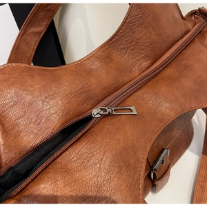 Detail view of brown vintage textured leather bag featuring a silver metal zipper and lining